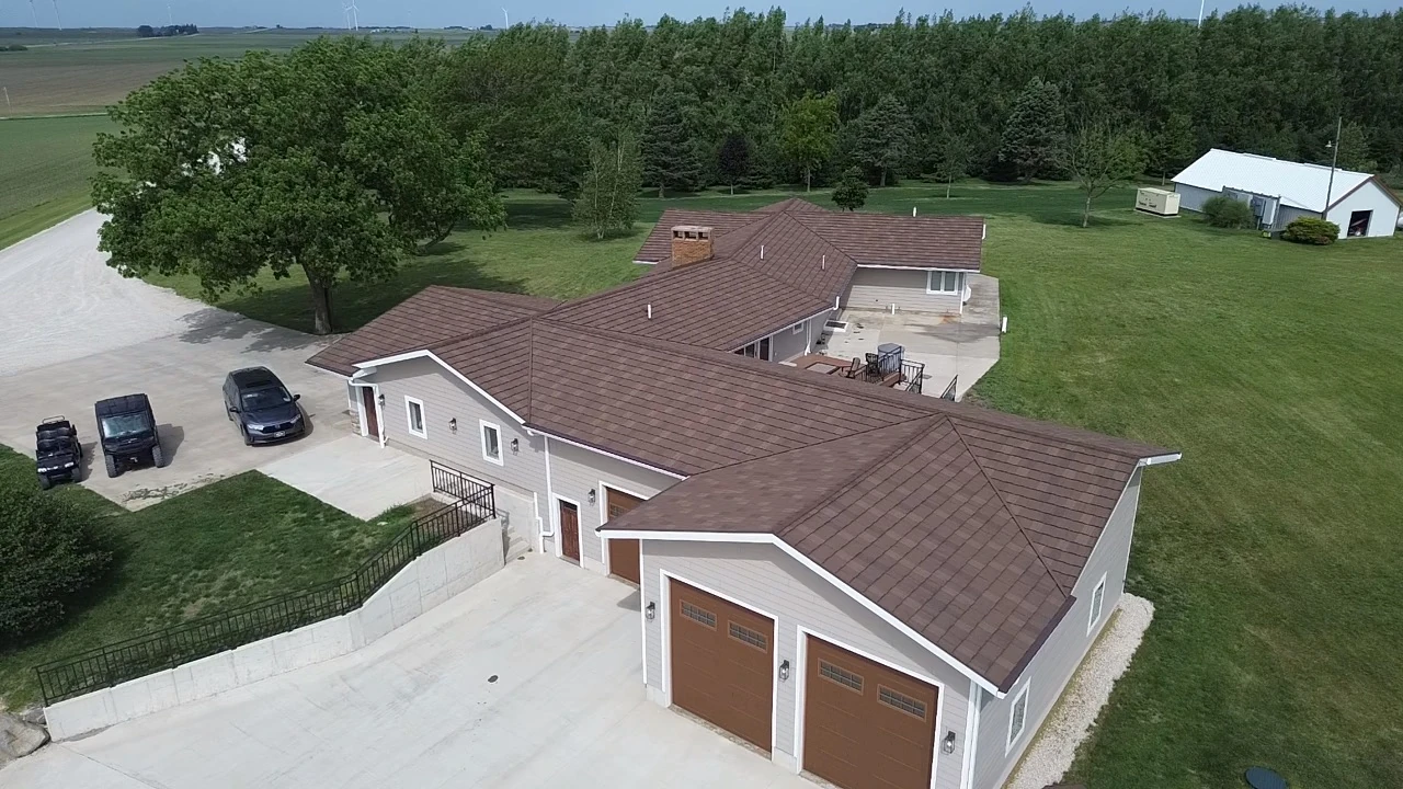 Aerial view of a residential property showing the roof, driveway, and surrounding lawn